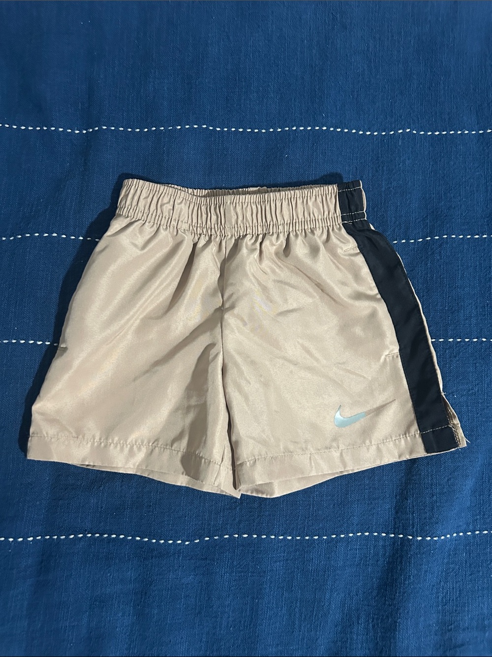 Nike Baby Boy Tan Athletic Shorts with Black Side Panels and Light Blue Swoosh